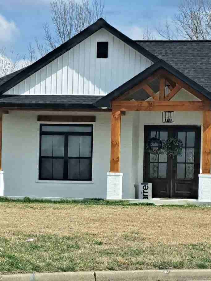 A white house with wooden pillars and black windows