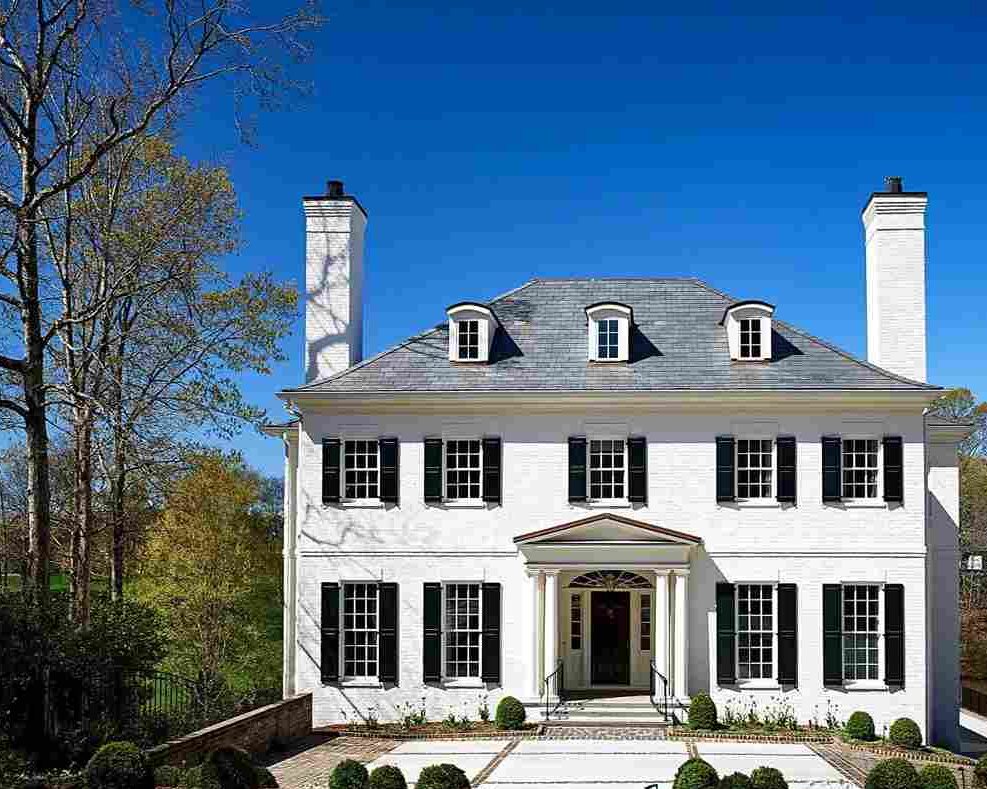 A white house with black shutter and windows and black front door and a stone pathway