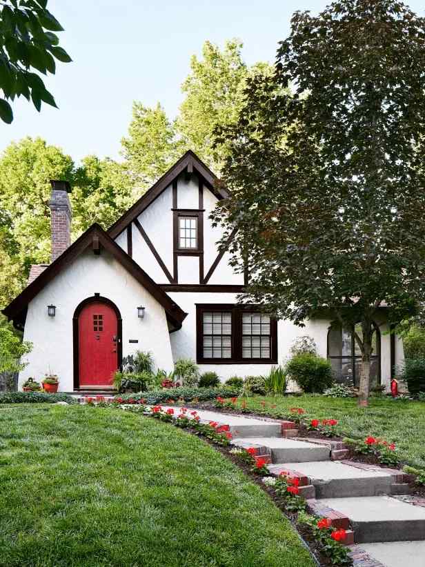 White stucco with red door and garden outside of the house 