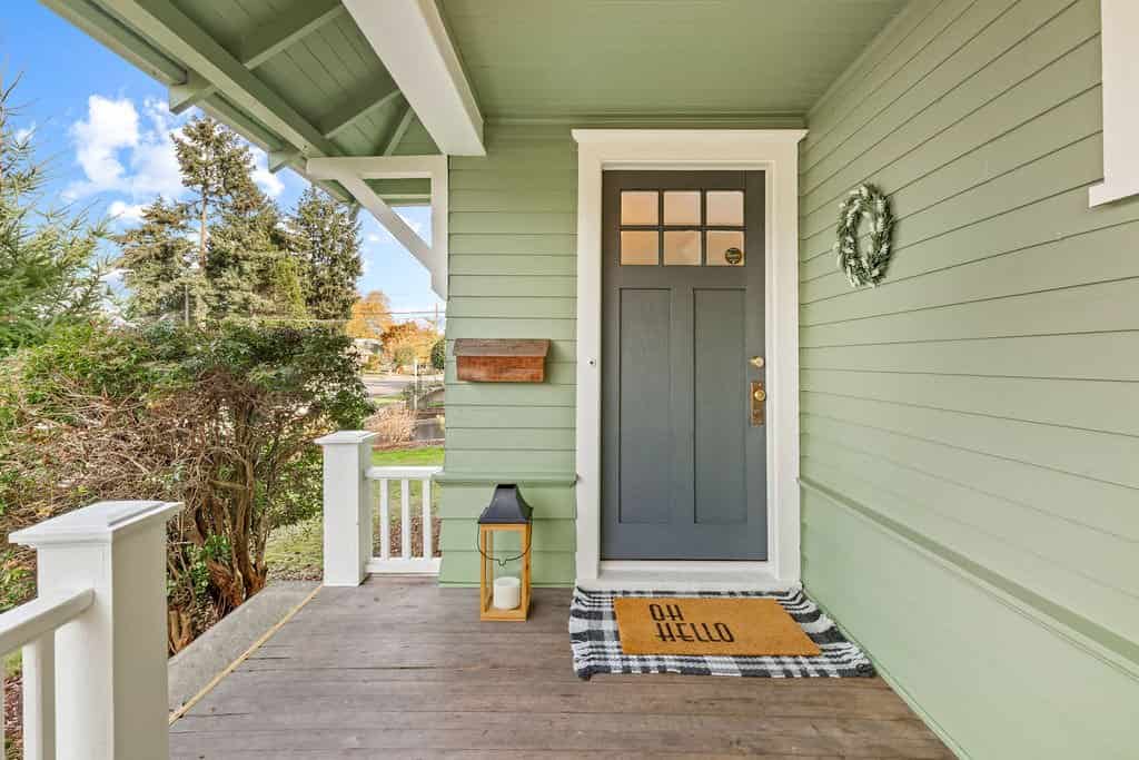 Wood decking and mat on the floor with green house and white trim