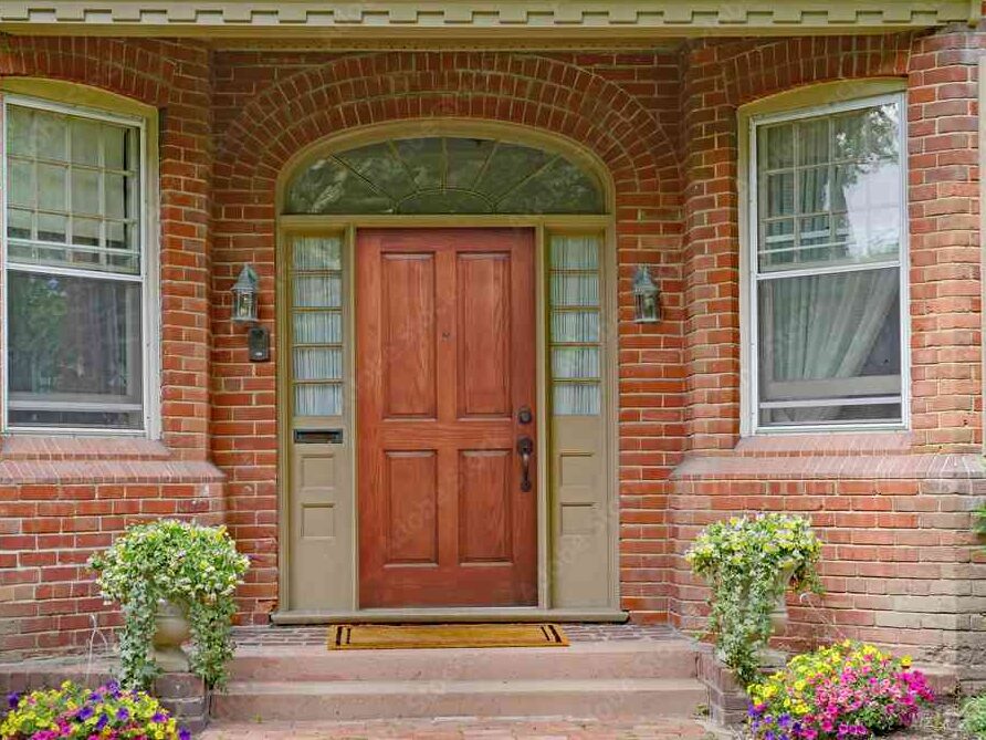 Wooden front door on brick house and white windows