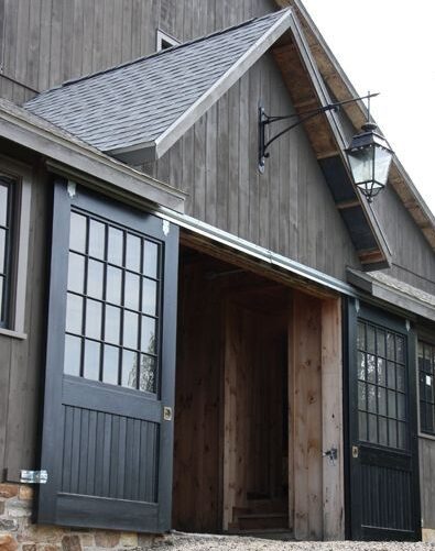 A black barn house with grey sidling door and light above the wall 