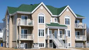Beige house with green roof and white windows and white stairs and railing