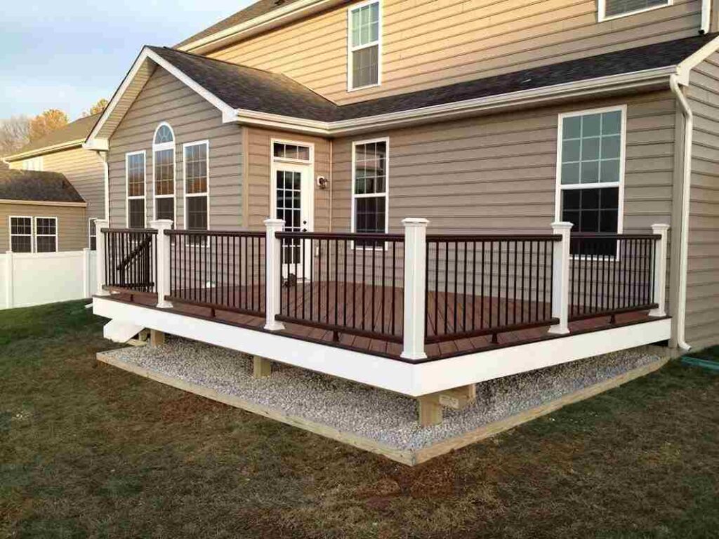 A tan house with wooden decking and white trim