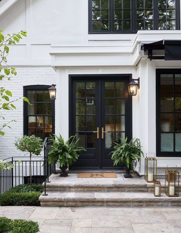 Black door on white house and lights on the wall