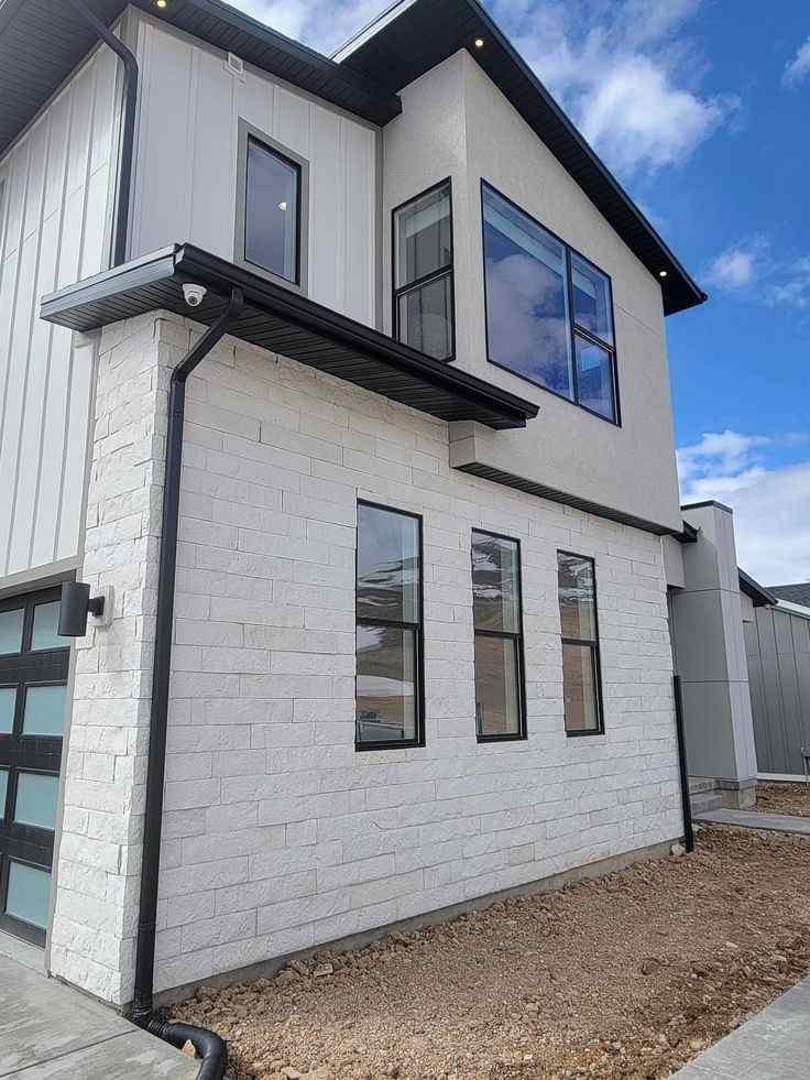 A white house with black trim and gutters and windows and black fascia