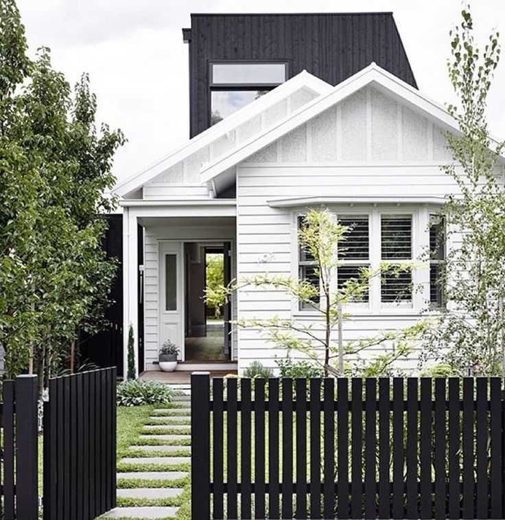 Black fencing around the white house and white framed windows