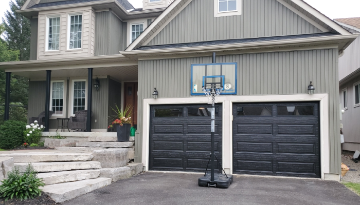 Black garage door on grey house with white trim and glass windows