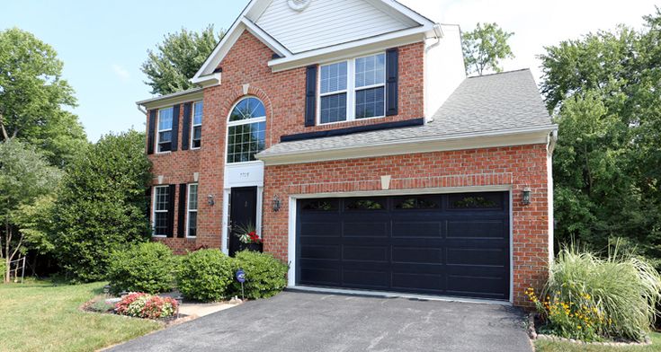 Black garage door on brick house with white trim glass window