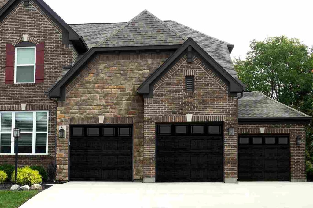 Brown brick house with white windows and black garage door and black roof 