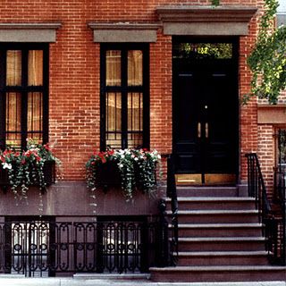 Black grid windows and stair with railing and black door on brick house