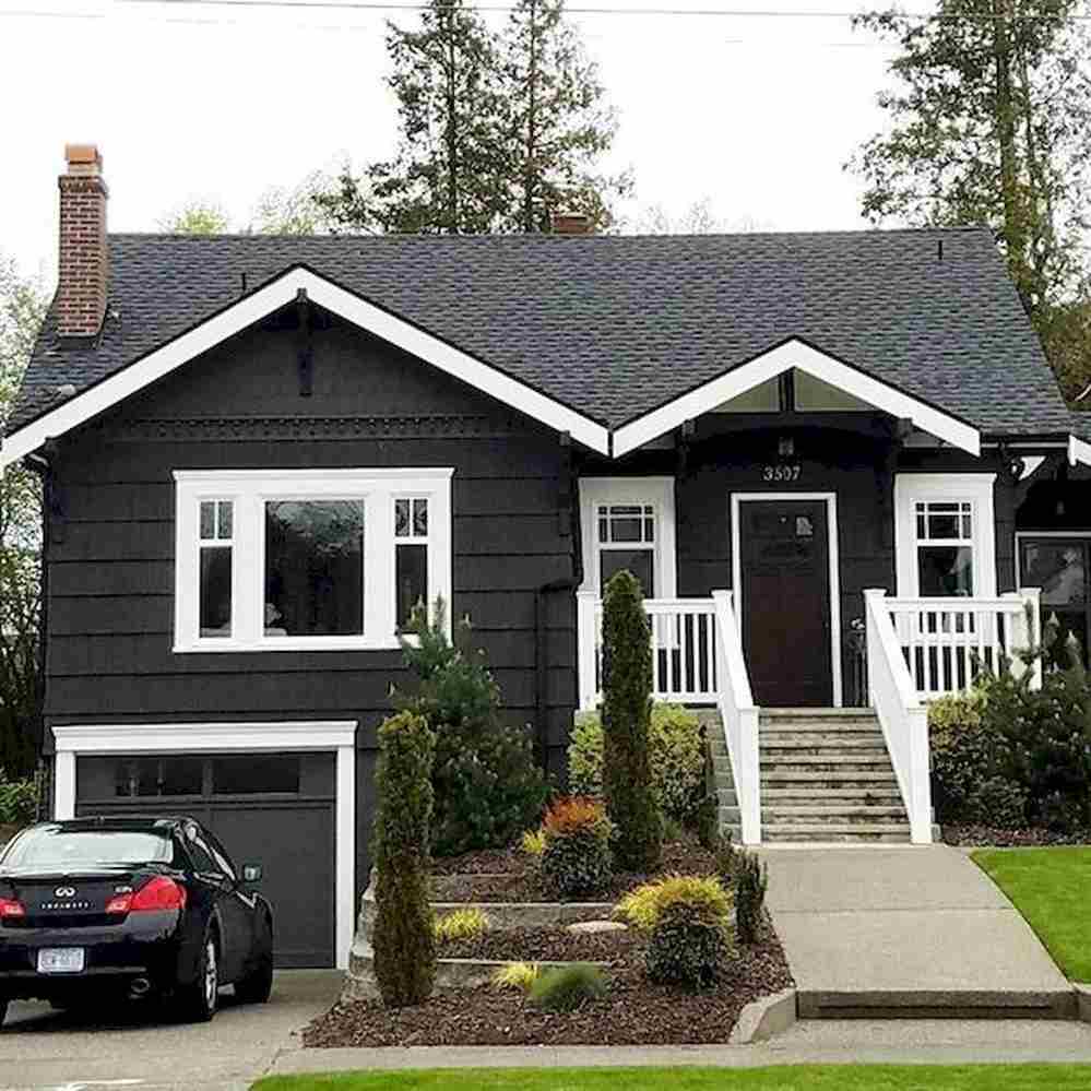 Black house with white trim and car outside of the house