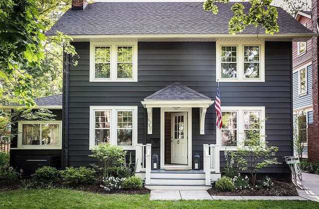 Black house with white window and white door and garden outside of the house