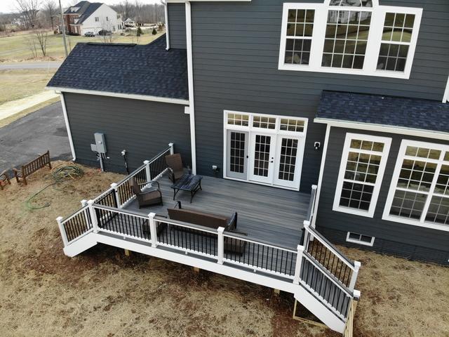 A wooden black porch on  grey house with white trim 