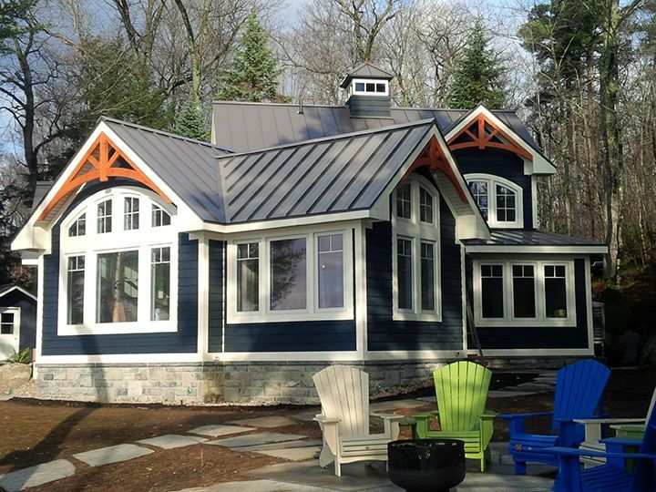 Blue house with black roof and colourful chairs outside of the house