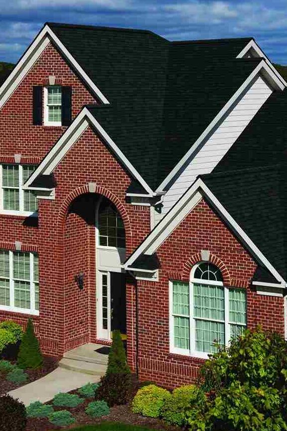 Red brick house with white framed windows and black roof
