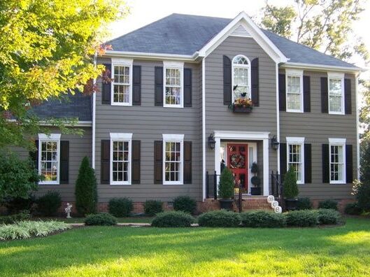 A grey house with black shutter and white trim windows and red door 