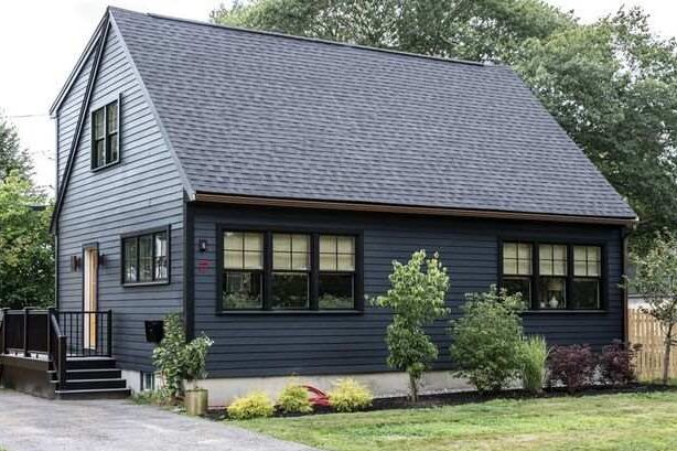 A blue house with black trim and black windows and garden outside of the house