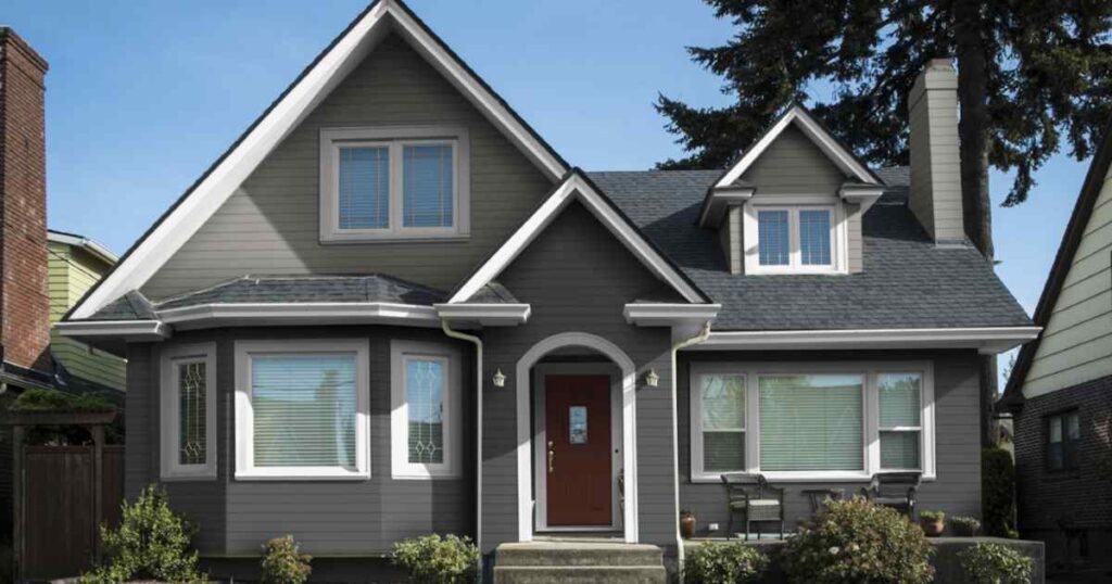 A grey house with black trim and white windows 