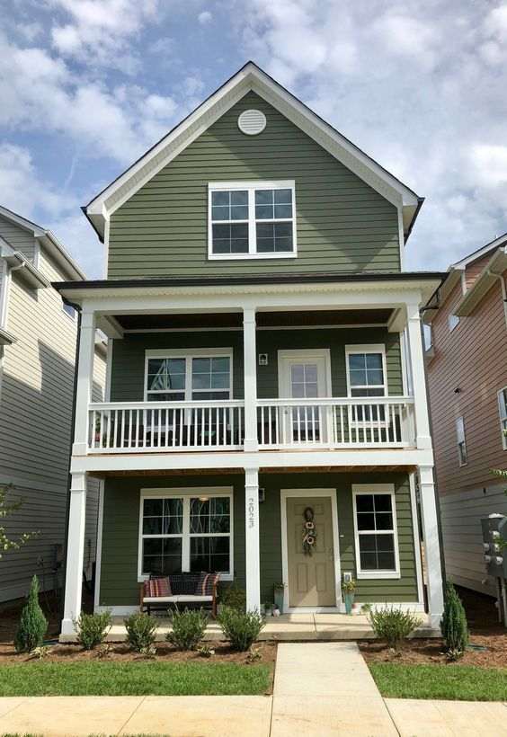 Green house with black trim with white windows and white balcony