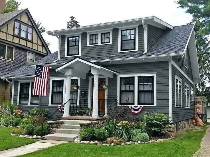 Grey house with black windows and white pillars and garden outside of the side