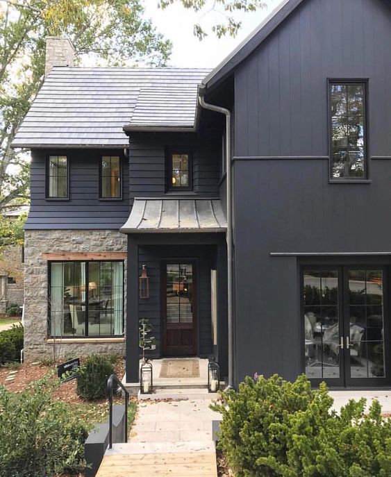 Blue house with black trim and windows and plants outside of the house