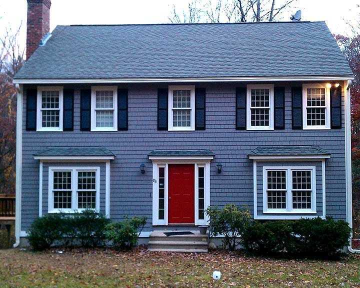 Blue house with black shutter and red door and white framed windows