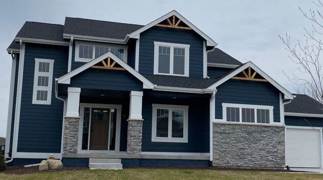 A blue house with grey stone cladding with white trim