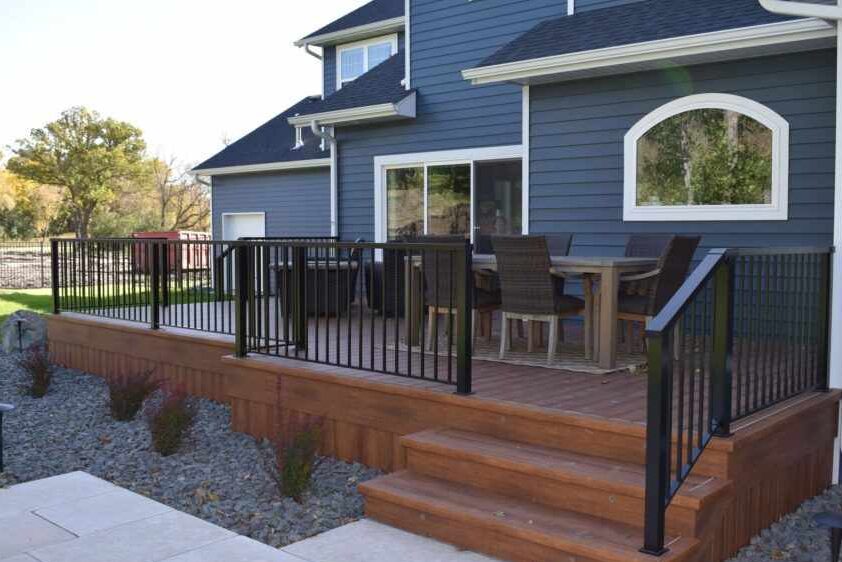 Blue house with wooden deck and table chair outside of the house