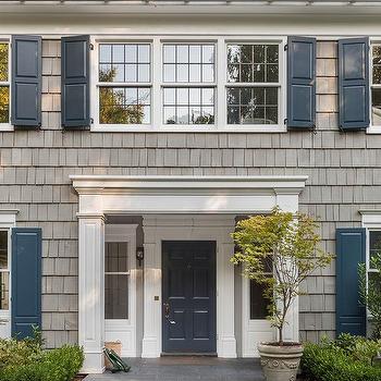 Tan house with wooden blue door and shutter and plant pot outside of the house