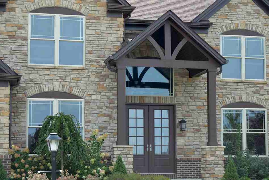 A tan brick house with wooden entryways and white windows