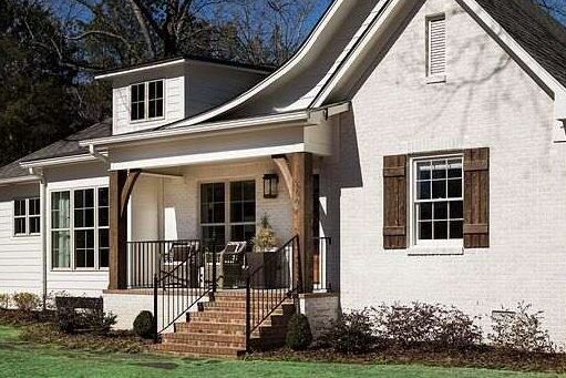 A white house with black railing and brown stairs and white trim