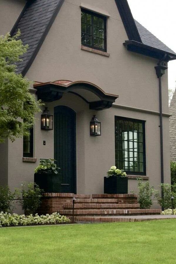 Brown house with black glass windows and gutters and lights on the both side of the house