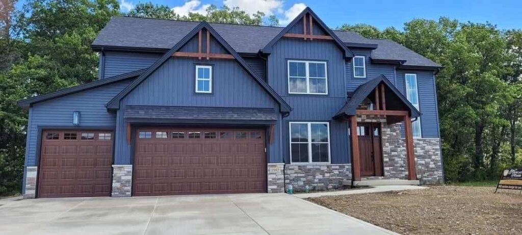 Blue house with wooden garage and with trim windows
