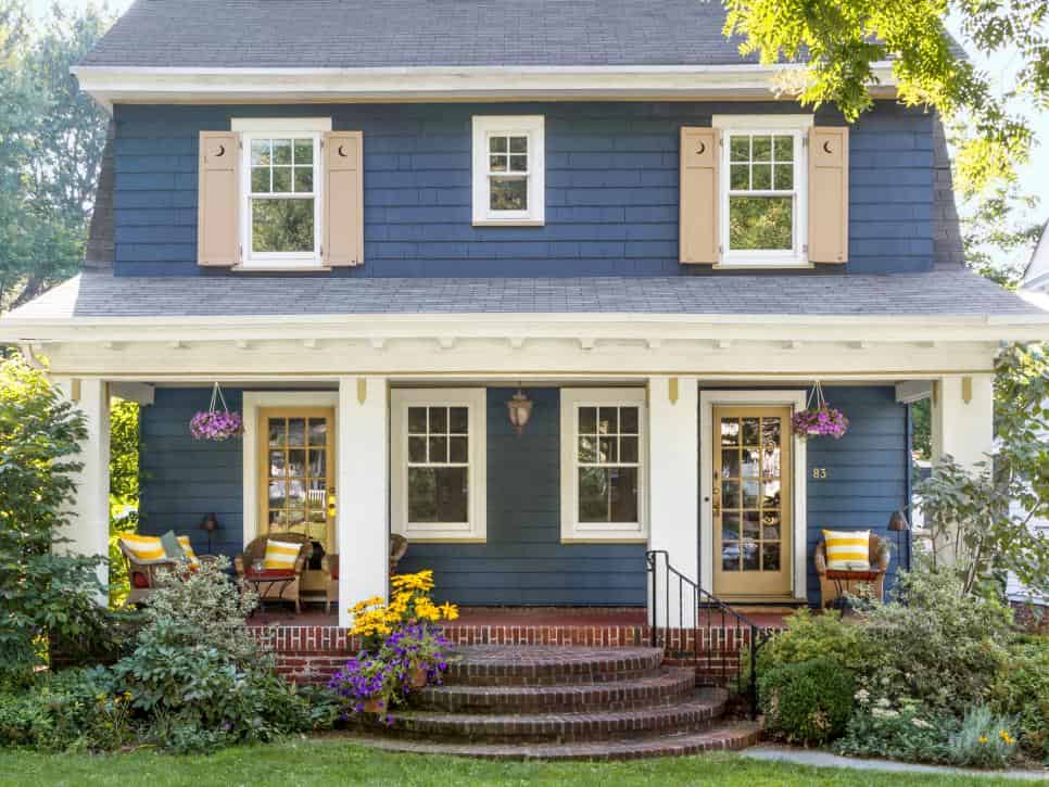 Dark blue house with wooden shutter and door and garden outside of the house