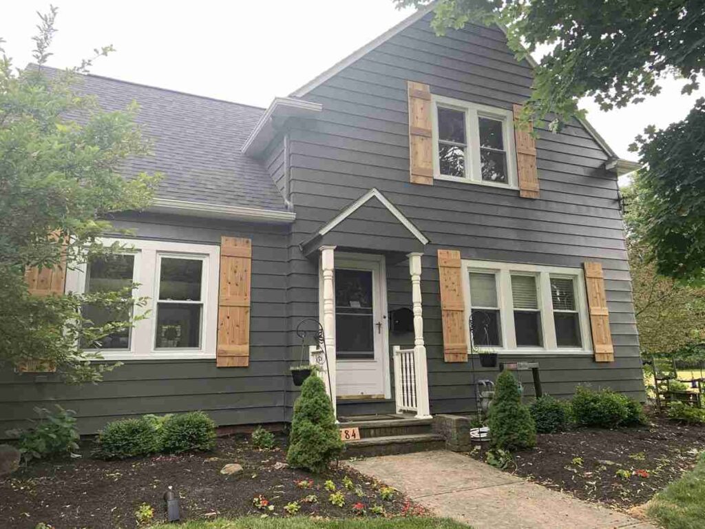Wooden shutter on grey house with white trim windows