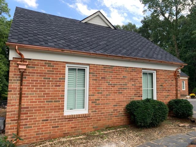 Copper gutter with red brick house and white trim windows