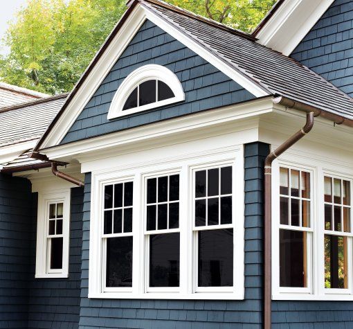 A blue house with white house with copper gutter and white trim windows