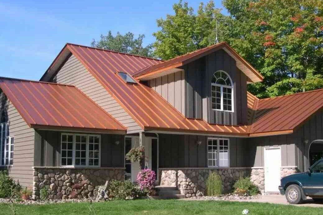 A tan house with cper roof and white trim window