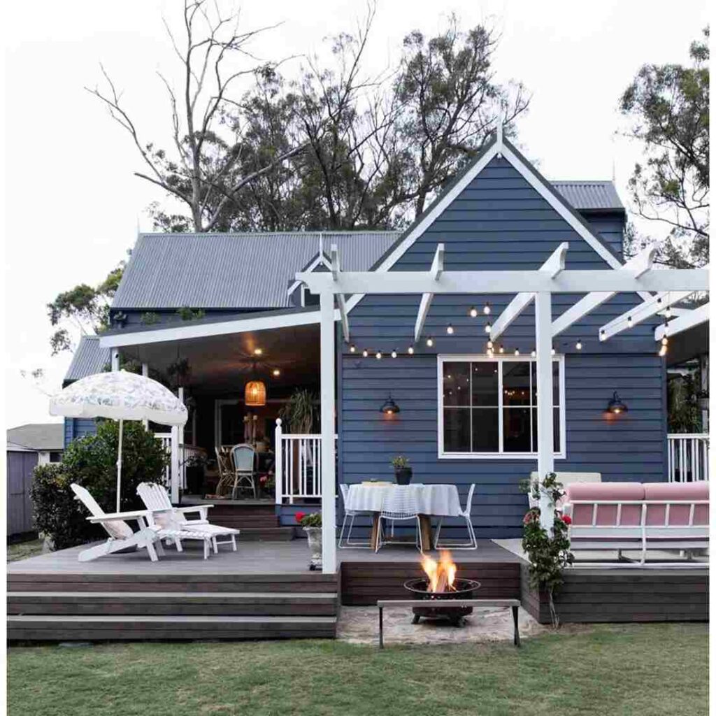 Dark blue house with pergola and chair table outside of the house