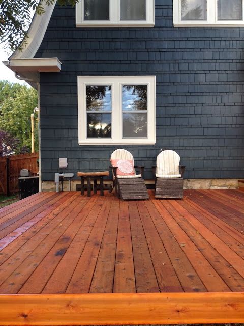 Dark blue house with wooden deck and chair on the deck