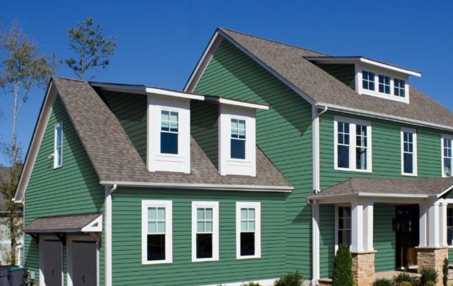 Dark green house with white trim windows and white and stone base pillars