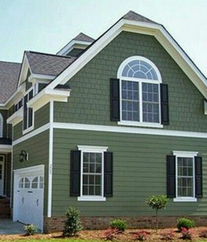 A green house with black shutters and white windows