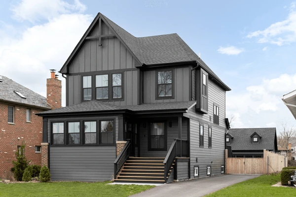 A gray house with black trim and staircase with black railing outside of the front door