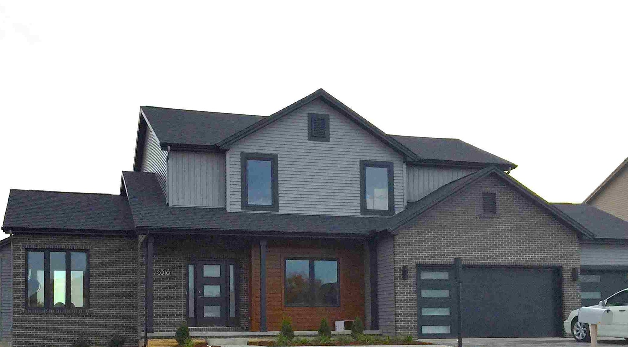 Black sidling on grey ouse and wooden door and black framed glass window and garage black door