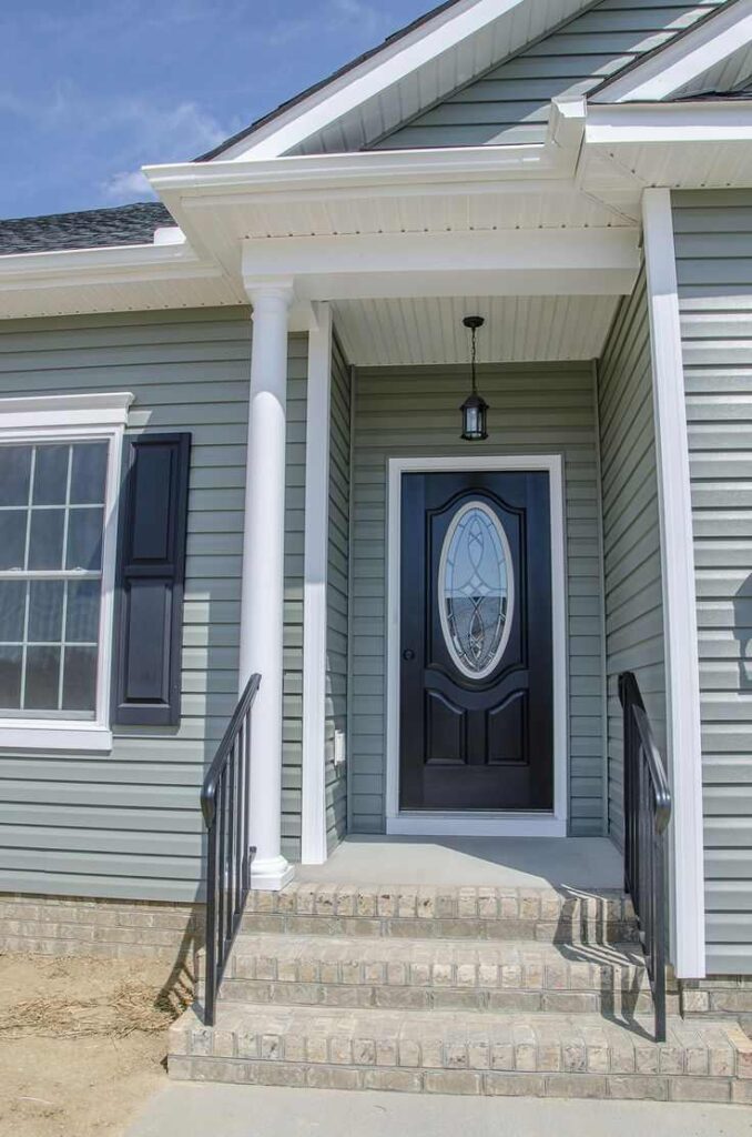 Light green house with black door and stair with black railings and white windows