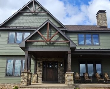 Green house with black trim and stone base pillars