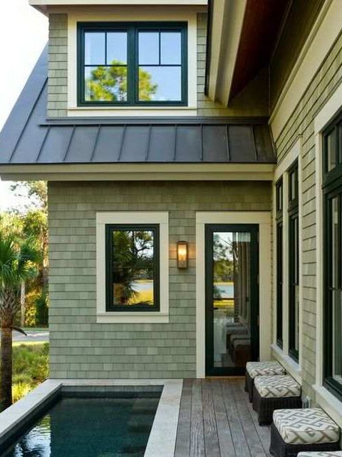 Light green house with black framed windows and light on the wall