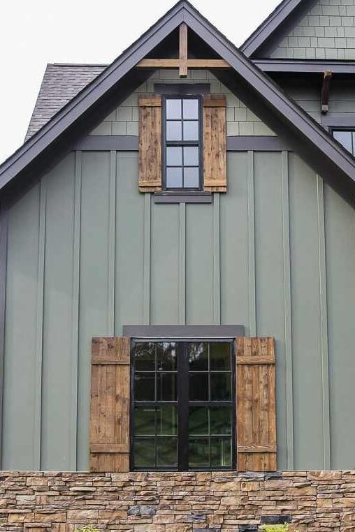 Sage green house with wooden shutter ans black trim windows 