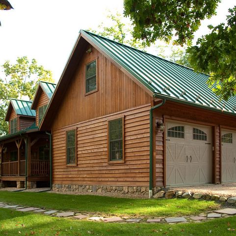 A brown house with green roof and glass windows and a front door and garden outside of the door